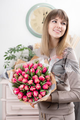 beautiful luxury bouquet of pink tulips flowers in woman hand. the work of the florist at a flower shop. cute lovely girl