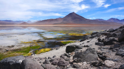 Amazing colorful lagoon with big rocks in the foreground and Andes mountains in the background, Altiplano of Bolivia