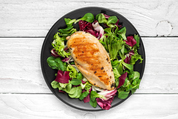 grilled chicken breast with mixed salad on a black plate