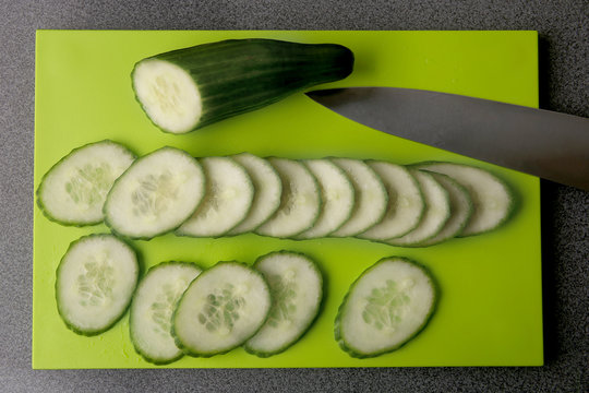 Sliced cucumber on cutting board. Fresh cucumber slices, top view.