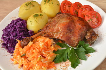 noga kaczki z ziemniakami, surówkami i pomidorem