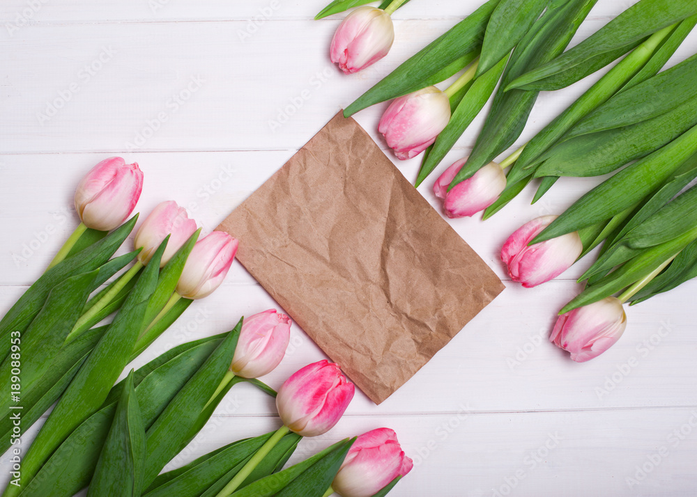 Wall mural pink tulips in two rows on a white wooden background and paper copy space for writing