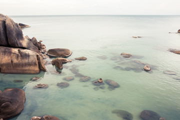 Tropical beach holidays landscape with calm turquoise sea and big round stones and rocks in sea   