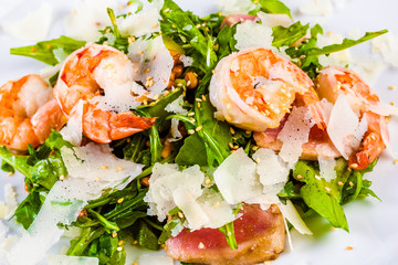 Rocket salad with shrimps, tuna and parmesan cheese on white plate