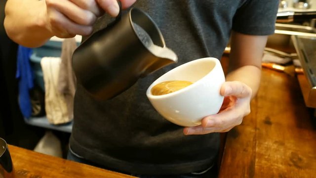 Close-up hand of barista made latte art at cafe. 
