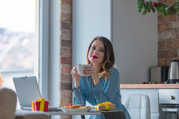 Portrait of redhead woman with cup of coffee or tea at kitchen