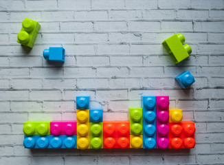 Plastic multicolored building blocks on white background with text space.