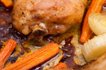 Roasted chicken, carrots, onion and garlic in metallic roaster oven pan