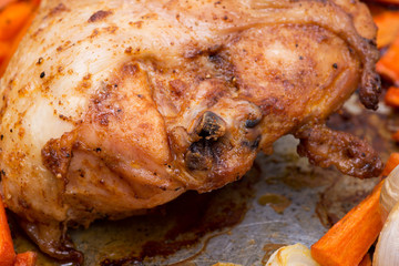 Roasted chicken, carrots, onion and garlic in metallic roaster oven pan