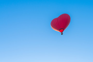 Red air in the form of a heart balloon in the blue sky