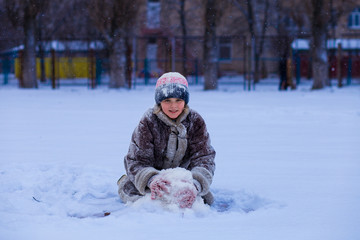 A cute little girl covered with snow has fun in winter park, wintertime