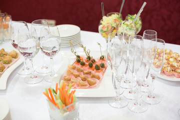 decoration, holidays, wedding concept. there is celebration table served with various snacks in pink paper cups and salad placed on the tall wine glasses