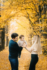 Fototapeta premium young family and newborn son posing for the camera in autumn park