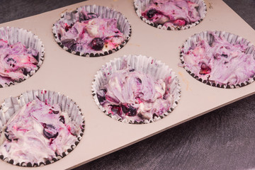 dough for muffins with berries in the form