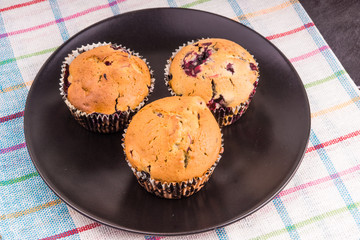 Fresh muffins on a dark plate close up