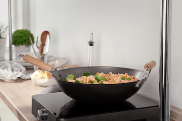 Delicious rice pilaf with broccoli in wok on electric cooker