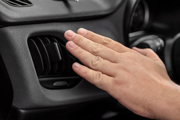 Man holding hand near air ventilation grille in car, closeup