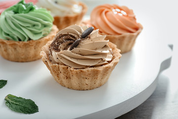 Board with tasty tartlets on table