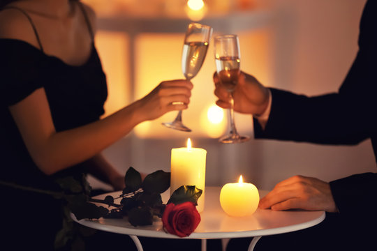 Young couple drinking wine while sitting at table with burning candles