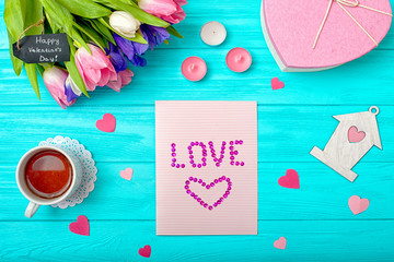 Valentines Day background with bouquet of tulips, a card with hearts and a gift.