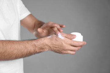 Man applying hand cream on grey background