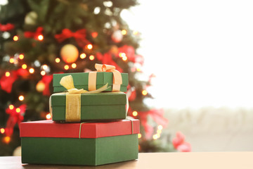 Wrapped gifts on table against blurred Christmas tree. Boxing day