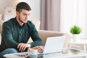 Young man using modern laptop at home