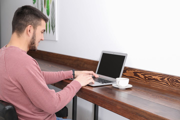 Young man using modern laptop in cafe