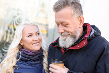 Fototapeta premium Happy mature couple drinking coffee outdoors on autumn day