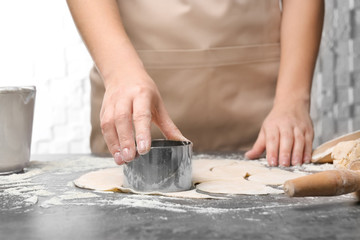 Woman cutting dough on table, closeup. Cooking dumplings