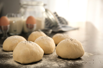 Unbaked buns with poppy seeds on table