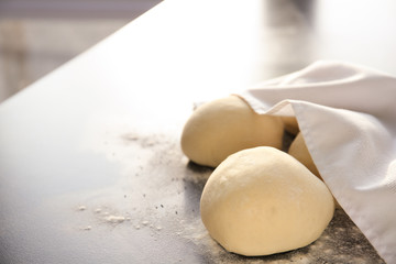 Unbaked buns covered with towel on table