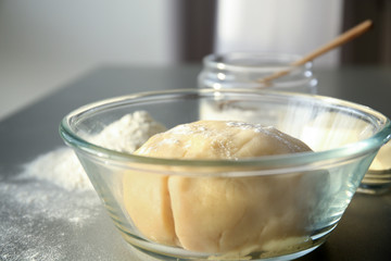 Bowl with raw dough on table
