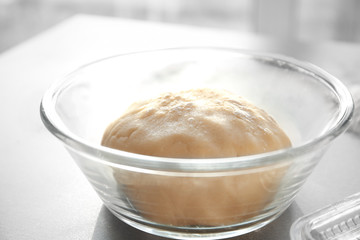 Bowl with raw dough on table
