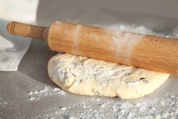 Raw dough and rolling pin on table