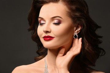 Fototapeta premium Beautiful woman with elegant earrings on dark background