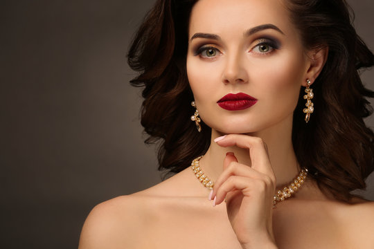 Beautiful woman with elegant jewelry on grey background