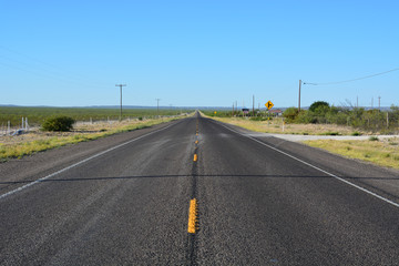 A lonely highway stretches off strait to the horizon in West Texas.