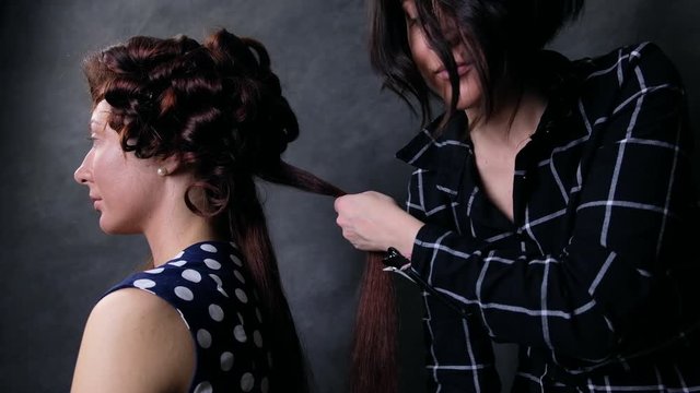 Closeup of hairdresser hands using curling styling on woman's  hair at studio or salon