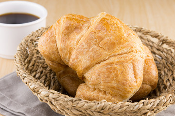 fresh croissants in the basket on wooden table