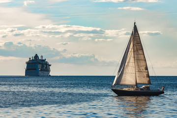 Blue sailboat against cruise liner