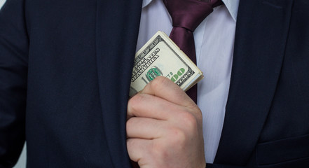 A businessman shows a sum of cash, puts it in his pocket of suit