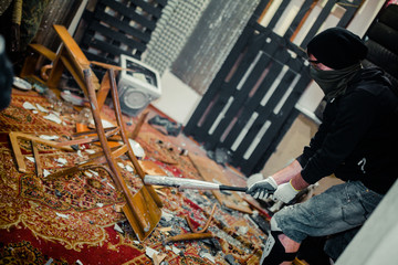 man in the rage room smashing chair and old computer with a baseball bat - obrazy, fototapety, plakaty