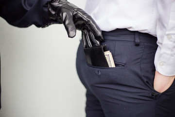 A thief takes a wallet with a cash from a pocket of a man in a suit, a businessman, a crime, a...