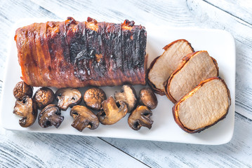 Pork loin wrapped in bacon with roasted mushrooms