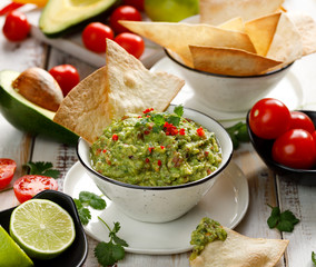 Guacamole,  traditional Mexican dip made of avocado, onion, tomatoes, coriander, chilli peppers, lime and salt with the addition of tortillas. Vegetarian food