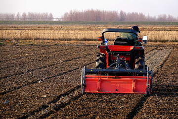 Farmer is plowing the soil with tractor in a field