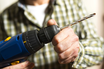 electrician works with battery drill machine DIY for installing radiator