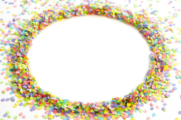 Round frame made of colored confetti. White background. Festive confetti.