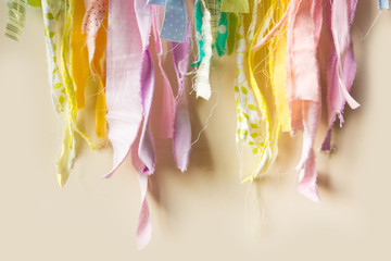 Ragged patches hang on the wall in the form of a garland. Rainbow made from pieces of cloth.